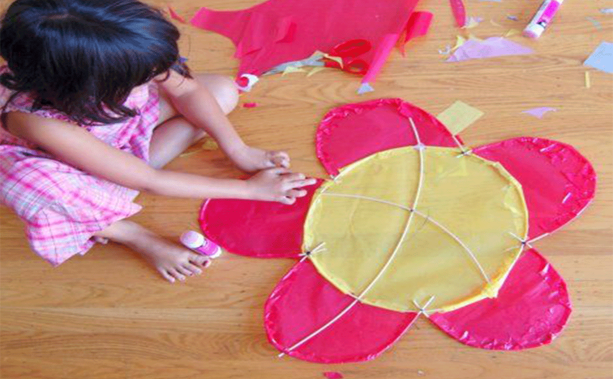 طفلة تصنع طائرة ورقية
