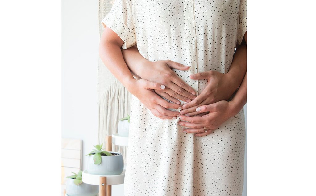 امرأة حامل تضع يديها وزوجها على بطنها