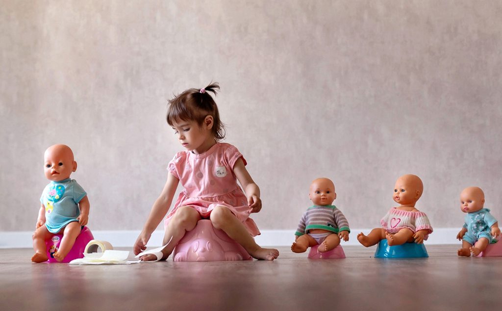 طفلة تجلس على النونية مع ألعابها