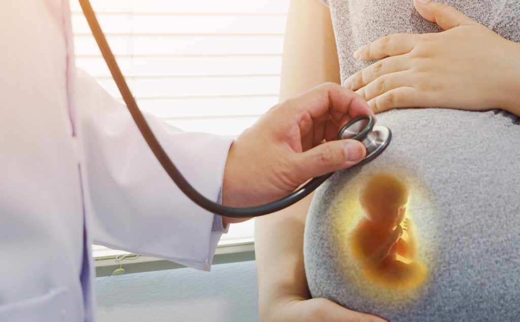 طبيب يضع السماعة على بطن امرأة حامل لتفقّد نبض الجنين