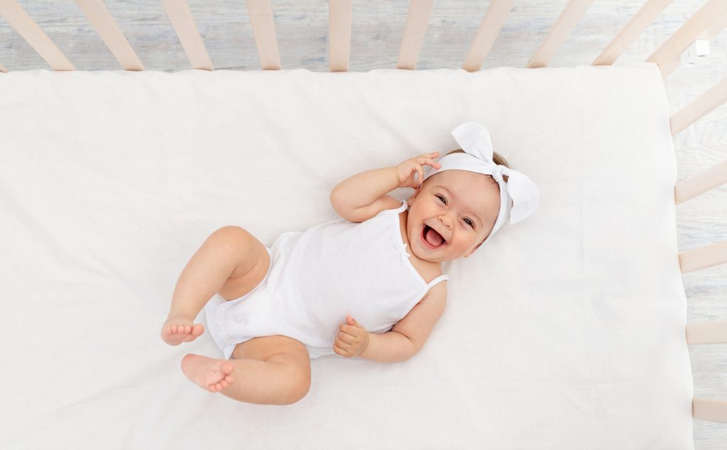 طفلة رضيع تضحك وهي مستلقية في سريرها