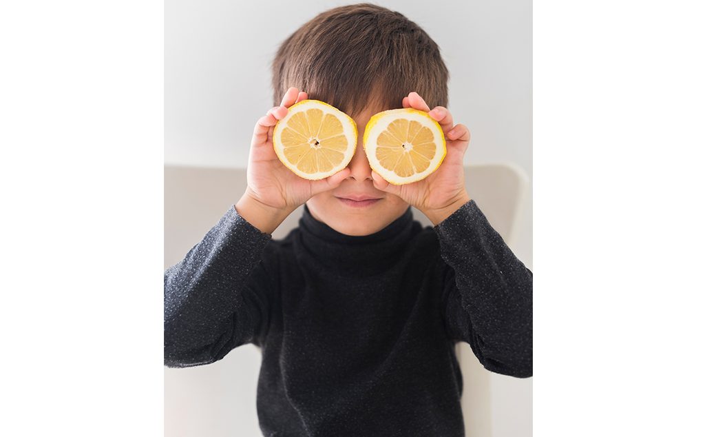 صورة لطفل صغير يضع الليمون على عينيه