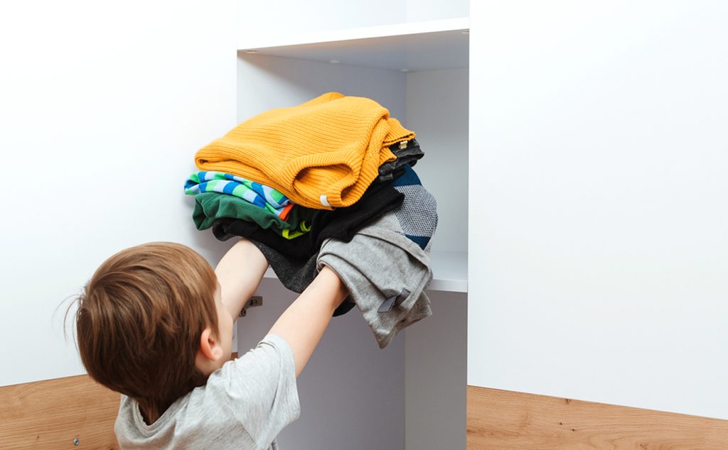 طفل يحاول ترتيب خزانة ملابسه