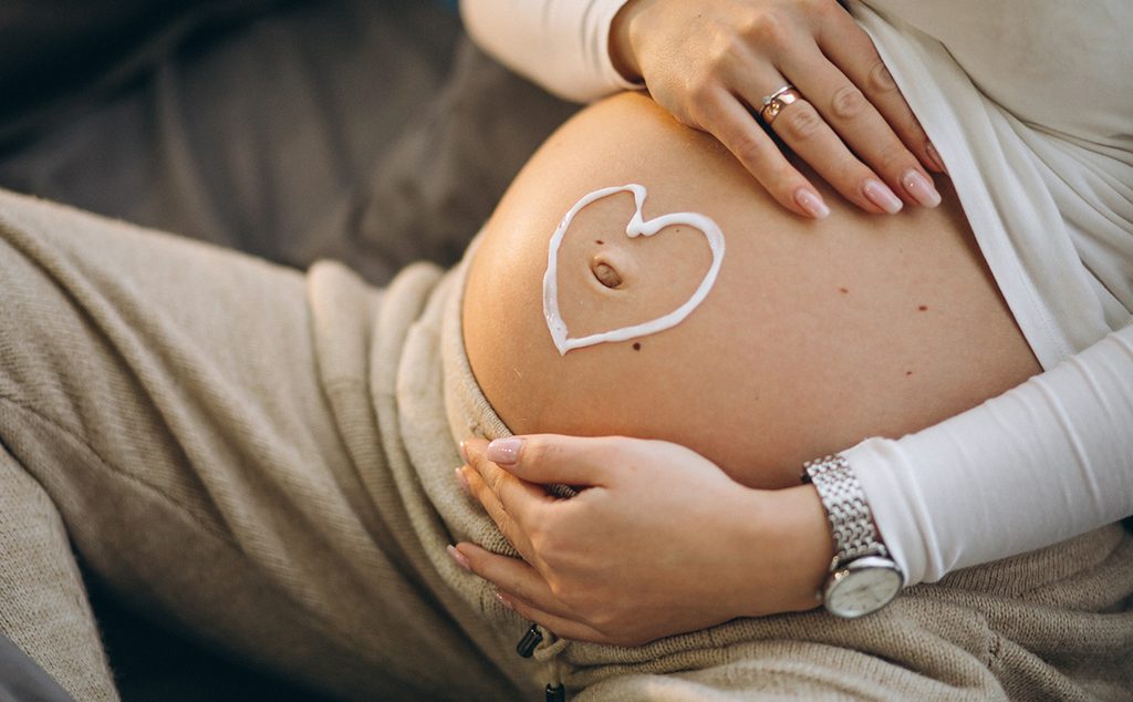 حامل تضع الكريمات على بطنها على شكل قلب