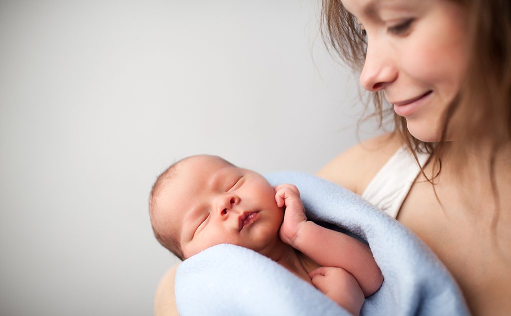 أم تحمل رضيعها بين يديها