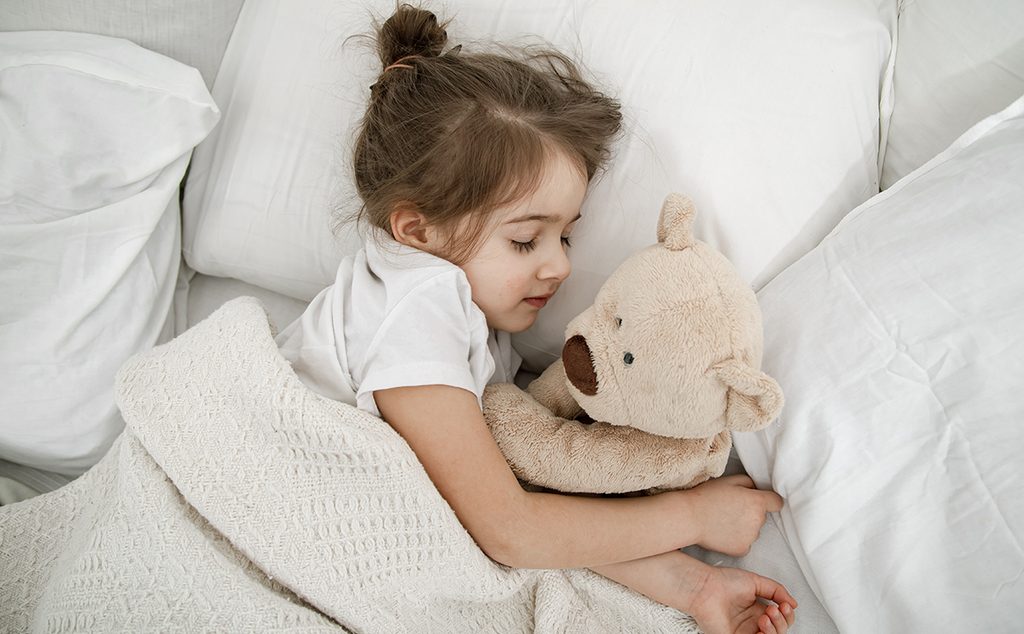 طفلة صغيرة تنام مع دميتها