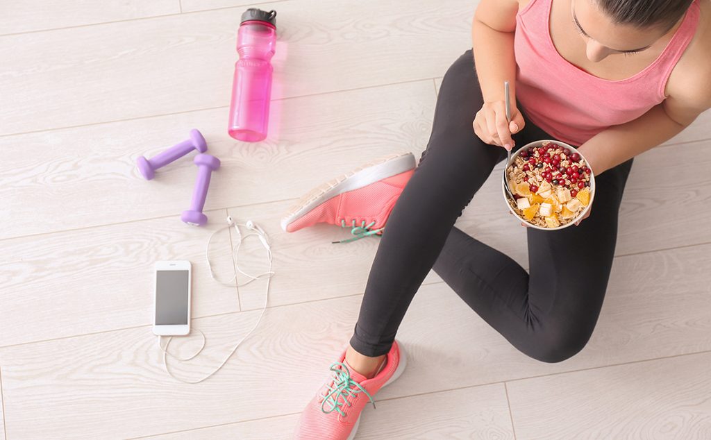 إمرأة تمارس الرياضة في المنزل وتتناول فطورًا صحيًّا