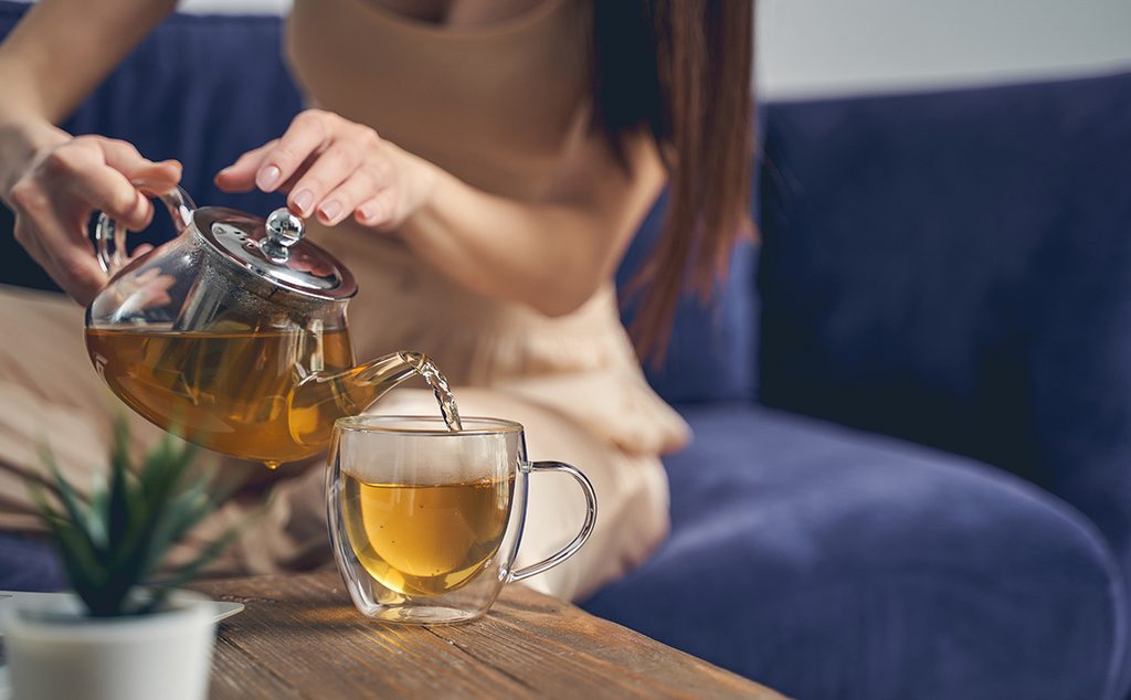 إمرأة تسكب شاي الميرمية في كوب