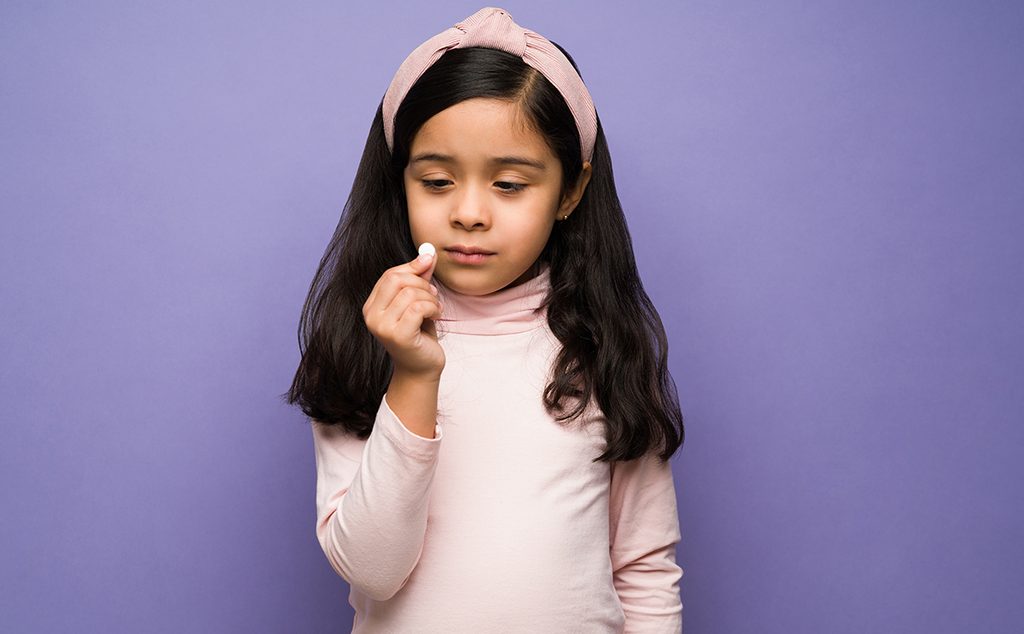 فتاة صغيرة تأخذ حبّة الدواء