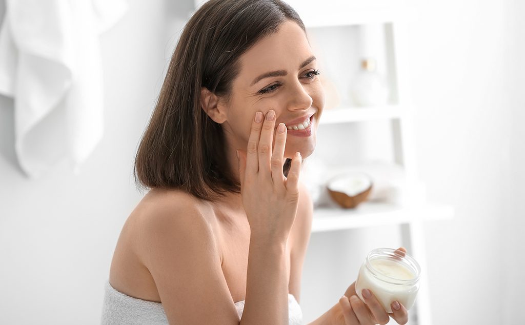امرأة تضع كريم بتركيبة طبيعية على بشرتها