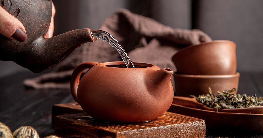 امرأة تسكب المياه الساخنة فوق عشبة المتة