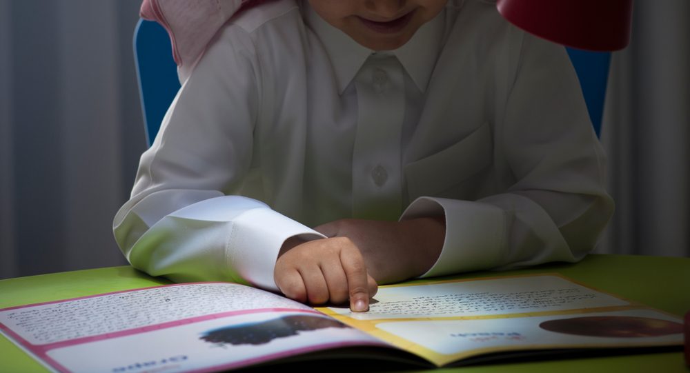 طفل صغير يقرأ في كتاب باللغة العربية