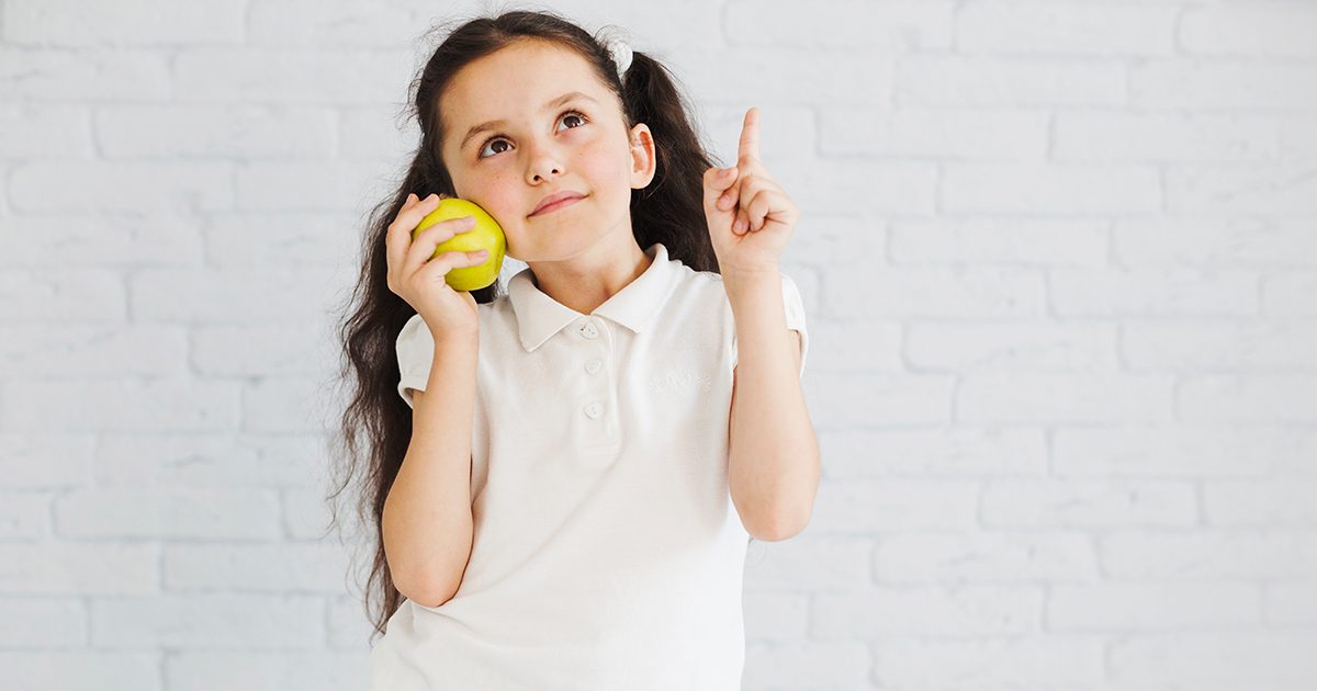 فتاة صغيرة تحمل تفاحة
