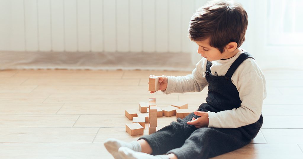 طفل صغير يلعب بالألعاب الخشبية