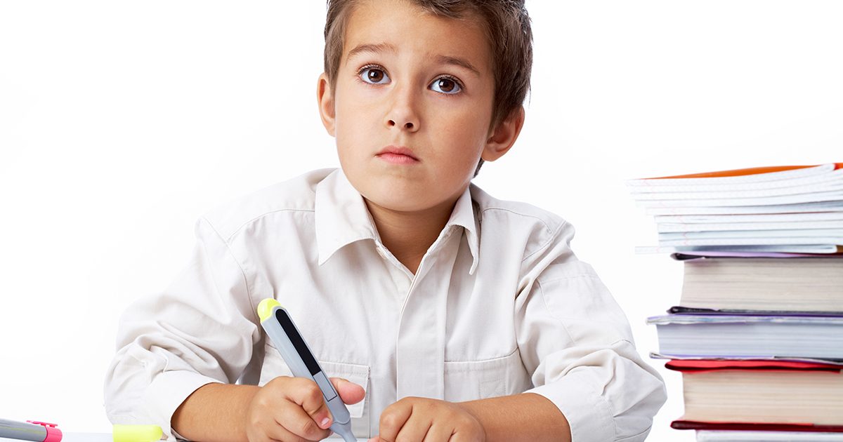 طفل يكتب على دفتره وهو مشتت