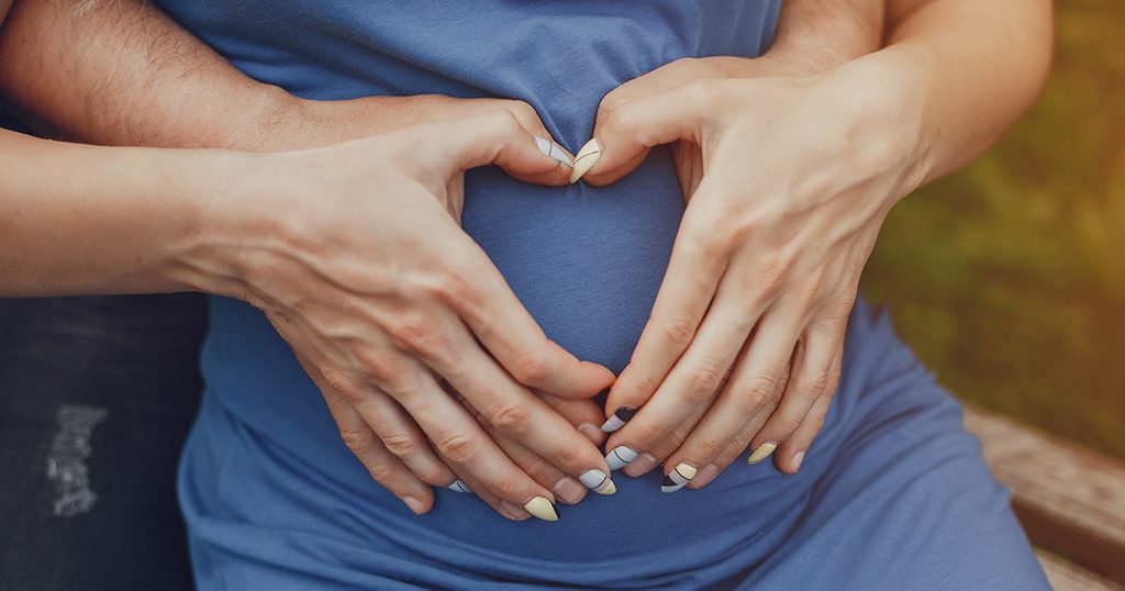 زوجان يضعان علامة قلب على بطن الزوجة الحامل