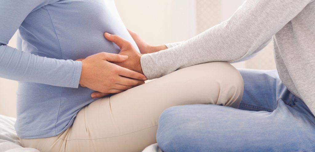 زوج يضع يديه على بطن زوجته الحامل