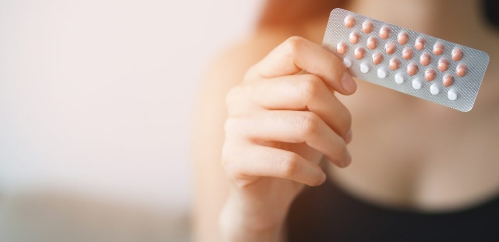 إمرأة بيدها حبوب منع الحمل