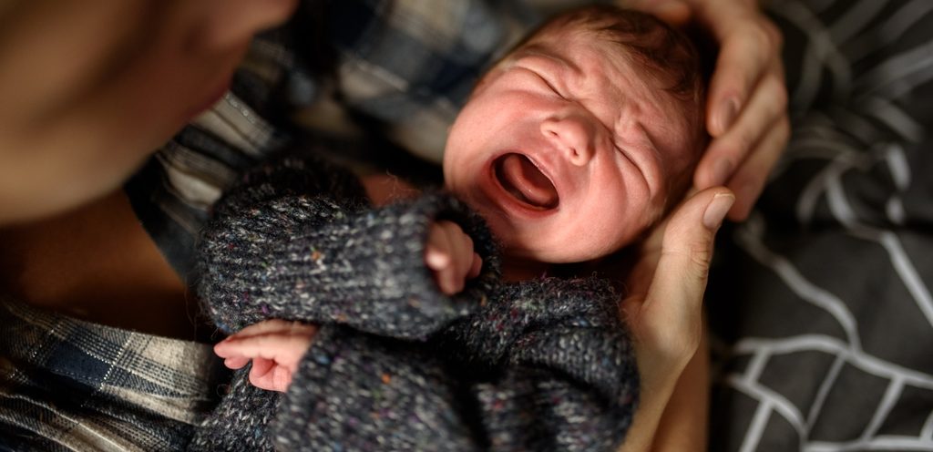 رضيع يبكي بحضن أمه