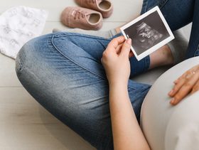 حامل تنظر إلى صورة الموجات فوق الصوتية لجنينها