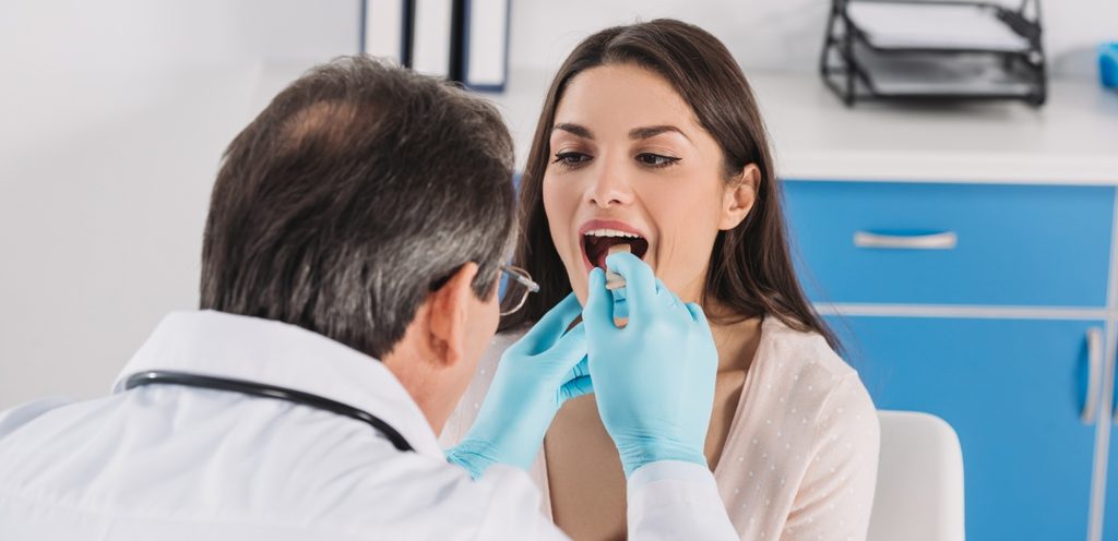 طبيب بفحص فم المريضة