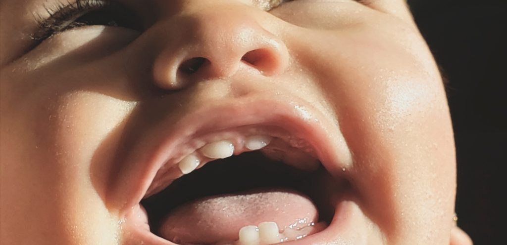 طفل رضيع يضحك وأسنانه بارزة