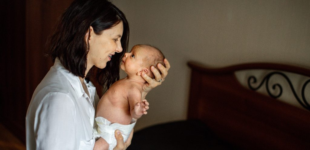 امرأة سعيدة تحمل طفلها قريبًا إلى وجهها