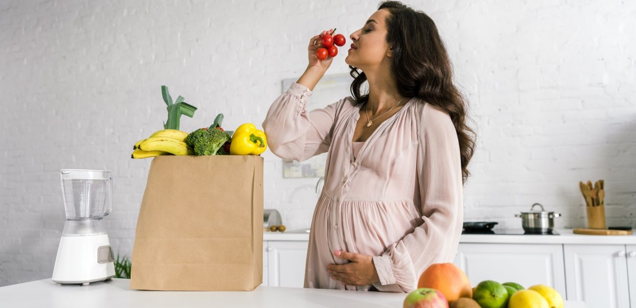 امرأة حامل تشمّ حبّات الطماطم