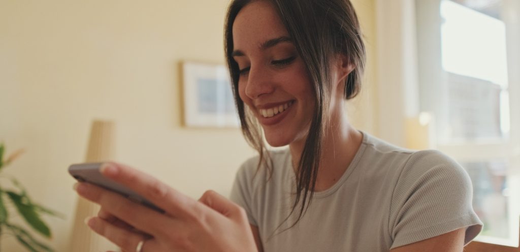 امرأة سعيدة تنظر إلى هاتفها