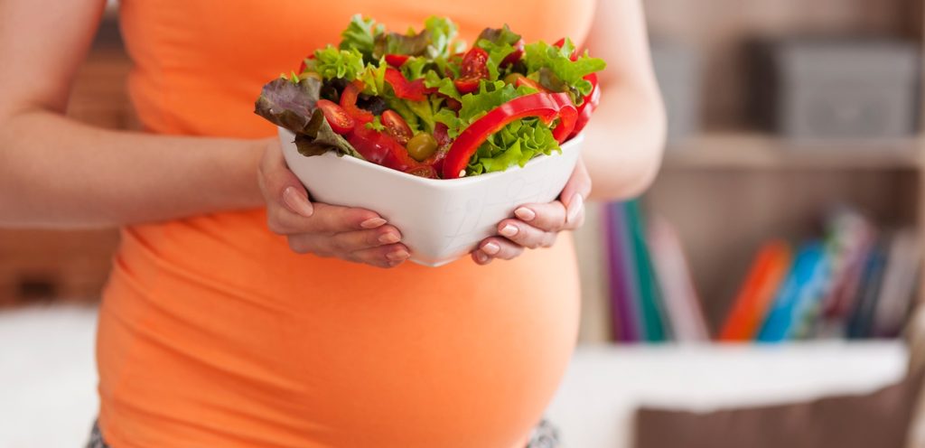 امرأة حامل تُمسك صحن من السلطة