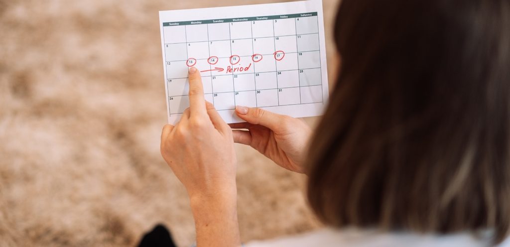 امرأة تُمسك بجدول دورتها الشهريّة
