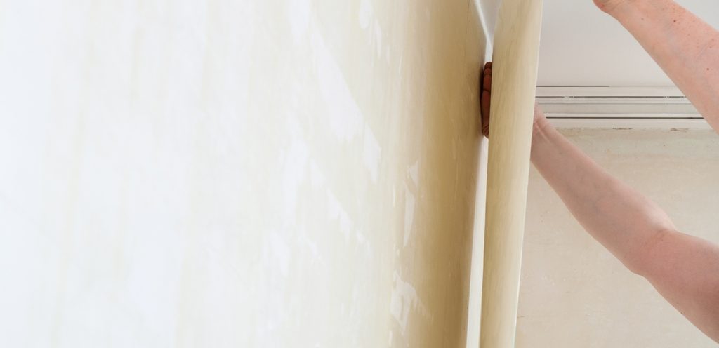 شخص يضع أو ينتزع ورق الجدران عن الحائط