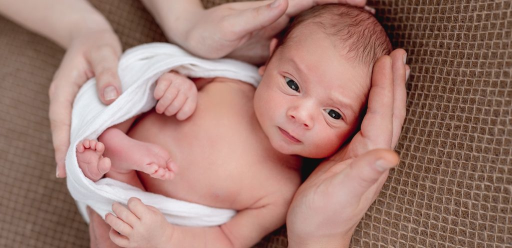 طفل حديث الولادة وأيدي والديه تحاوطه