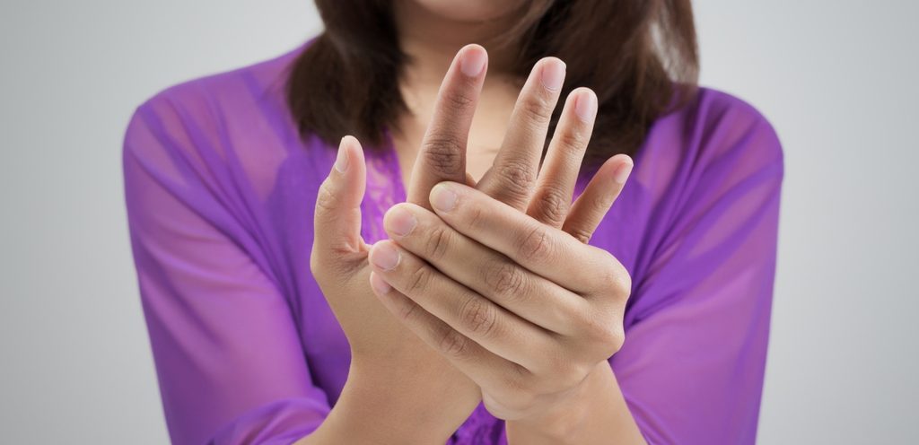 امرأة ترتدي اللون النفسجي تشعر بألم في يدها