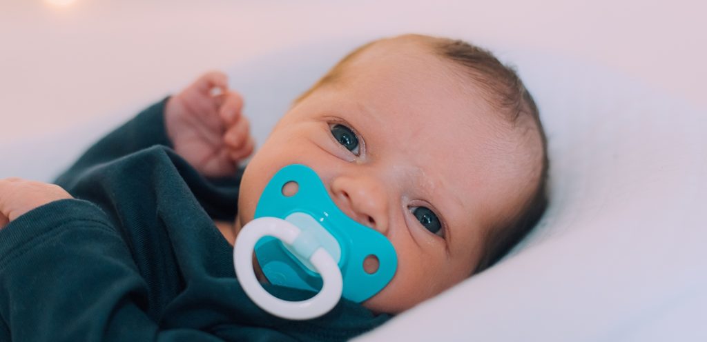 طفل رضيع وفي فمه لهاية زرقاء