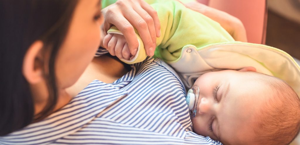 أمّ تضع طفلها الرضيع نائمًا على صدرها