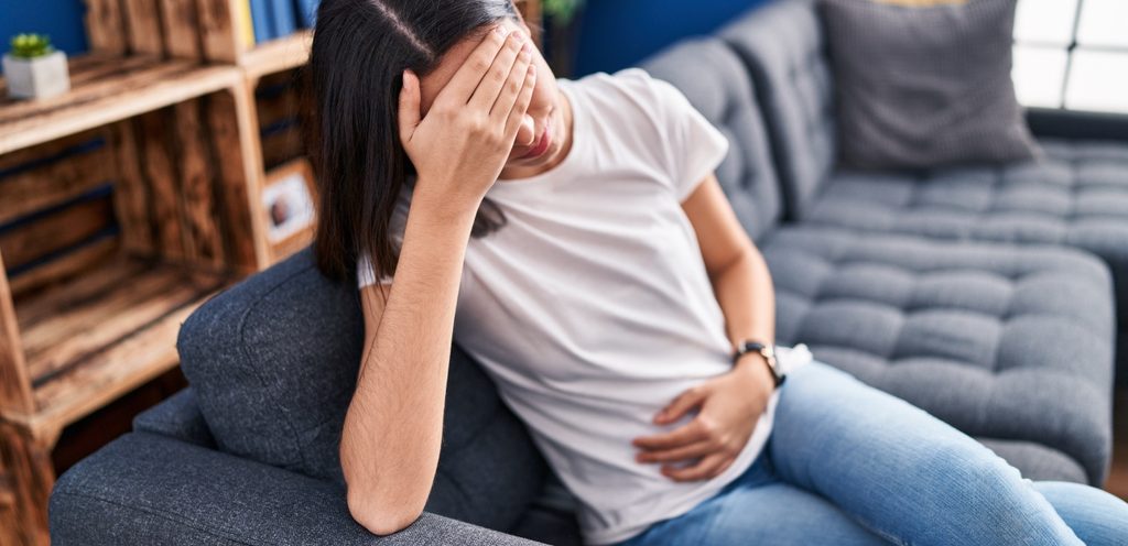 امرأة مُتعبة تشعر بآلام الرأس والبطن