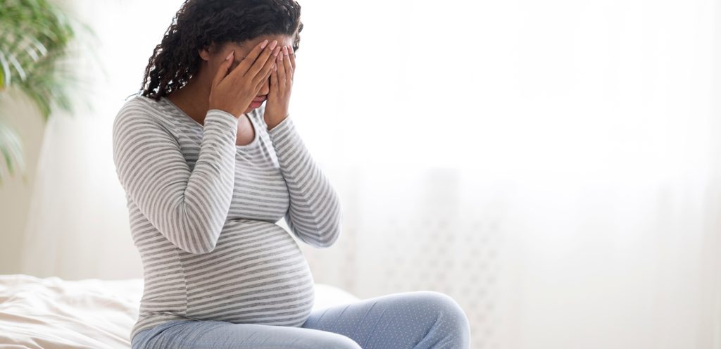 امرأة حامل تضع يديها على رأسها وتُعاني من التعب