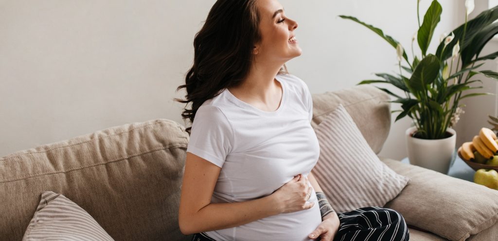 امرأة حامل سعيدة تضع يديها على بطنها
