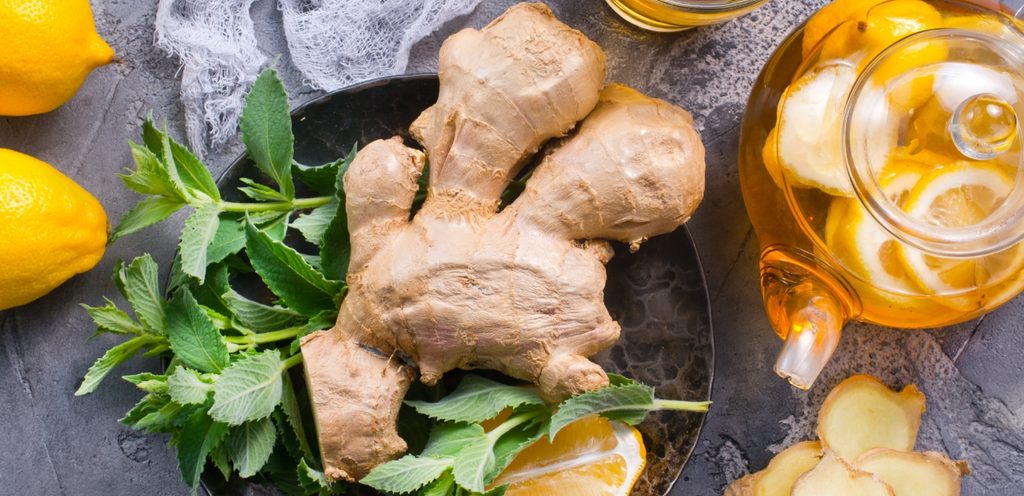 قطع من الزنجبيل بجانبها إبريق من الشاي والليمون