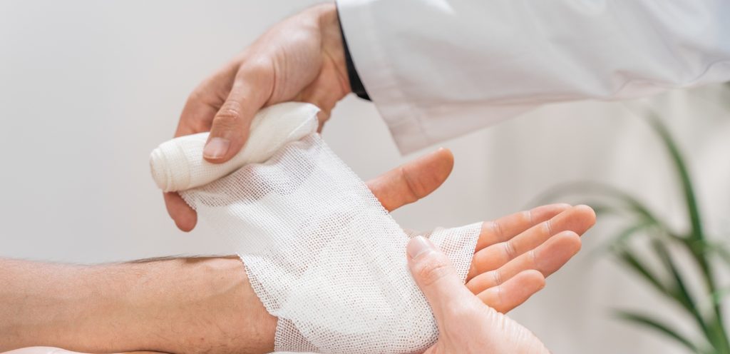 طبيب يلفّ يد مريضه بالشاش الطبّي