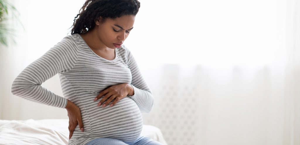 امرأة حامل تضع يد على ظهرها والأخرى على بطنها