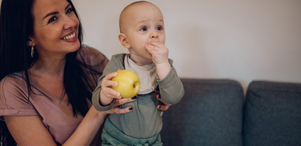 أم تحمل طفلها وهو يأكل التفاح