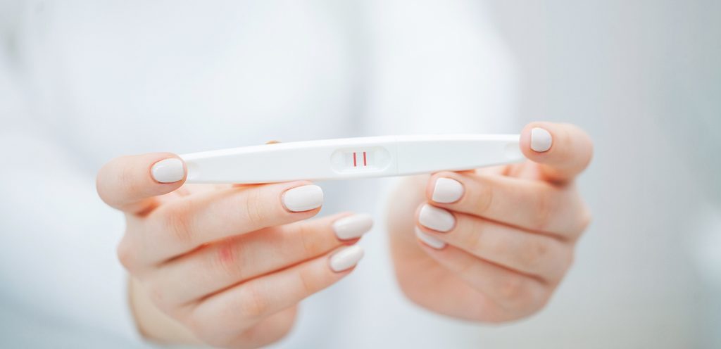 يدي امرأة تُمسكان اختبار حمل