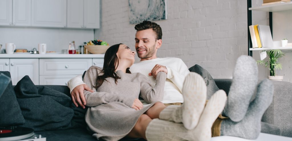 زوجان يجلسان بجانب بعضهما البعض ويمدّان رجليهما وينظران إلى بعضهما البعض بسعادة