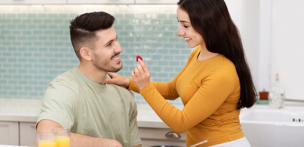 امرأة تُقدّم الفراولة لزوجها وهما مبتسمان