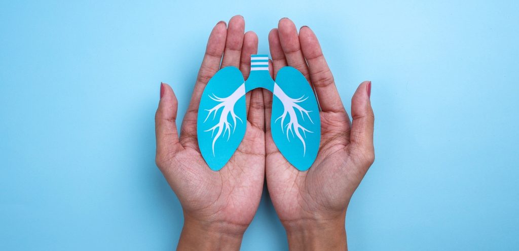 امرأة تمسك بين يديها صورة تحمل شكل الرئتين باللون الأزرق