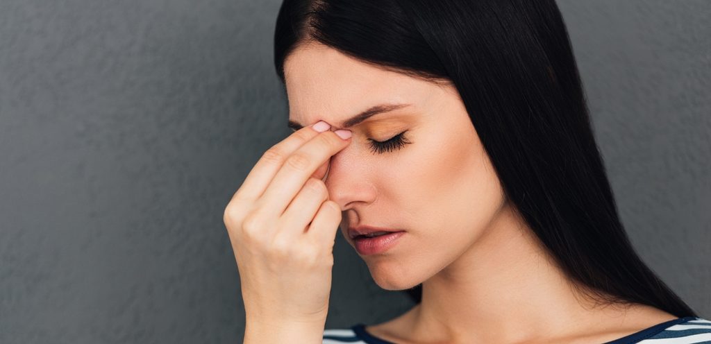 امرأة تضع يدها بين حاجبيها وتغمض عينيها