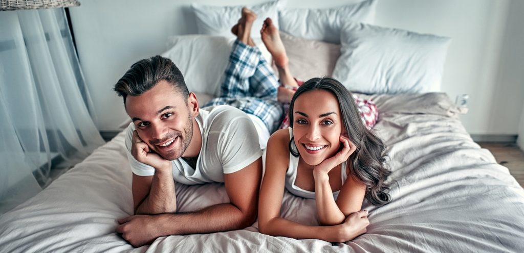 زوجان سعيدان مستلقيان على بطنهما على السرير