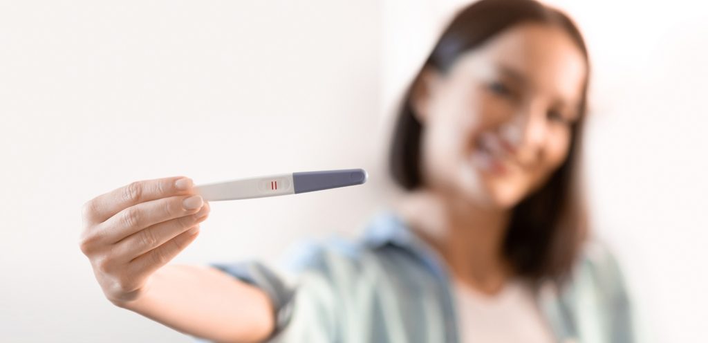 امرأة تُظهر اختبار حمل إيجابي بسعادة